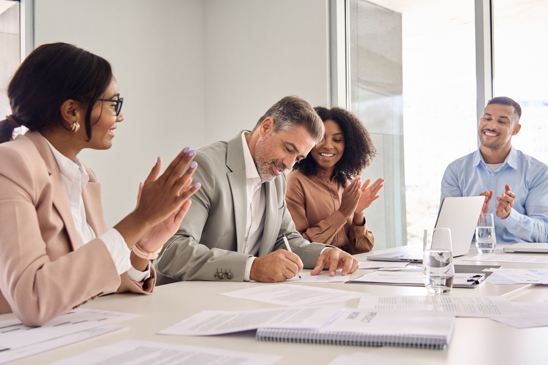 A group of people are sitting at a table clapping their hands.