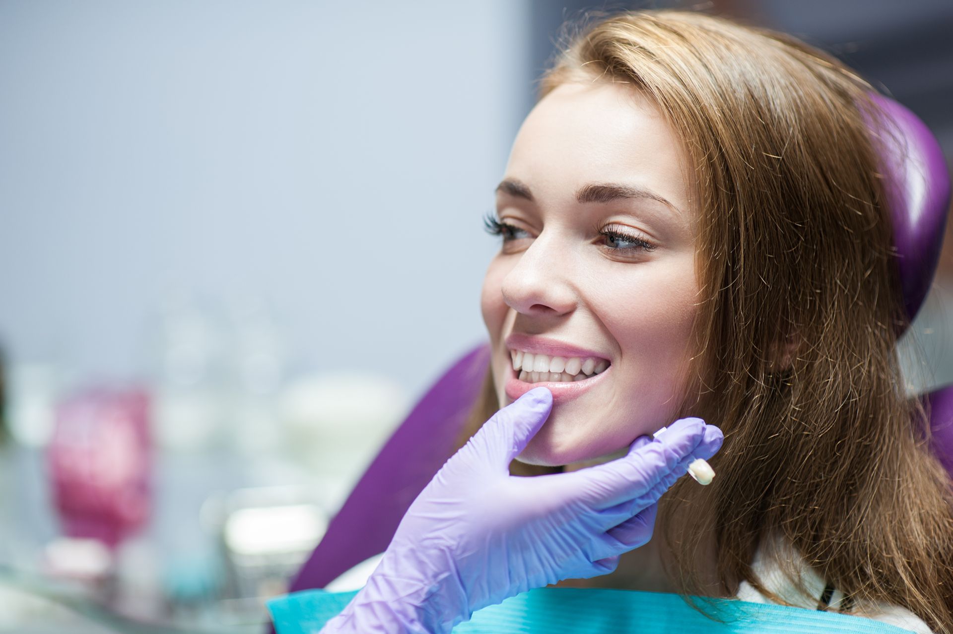 A smiling woman sitting in a dentist chair, ready for her dental crowns procedure.