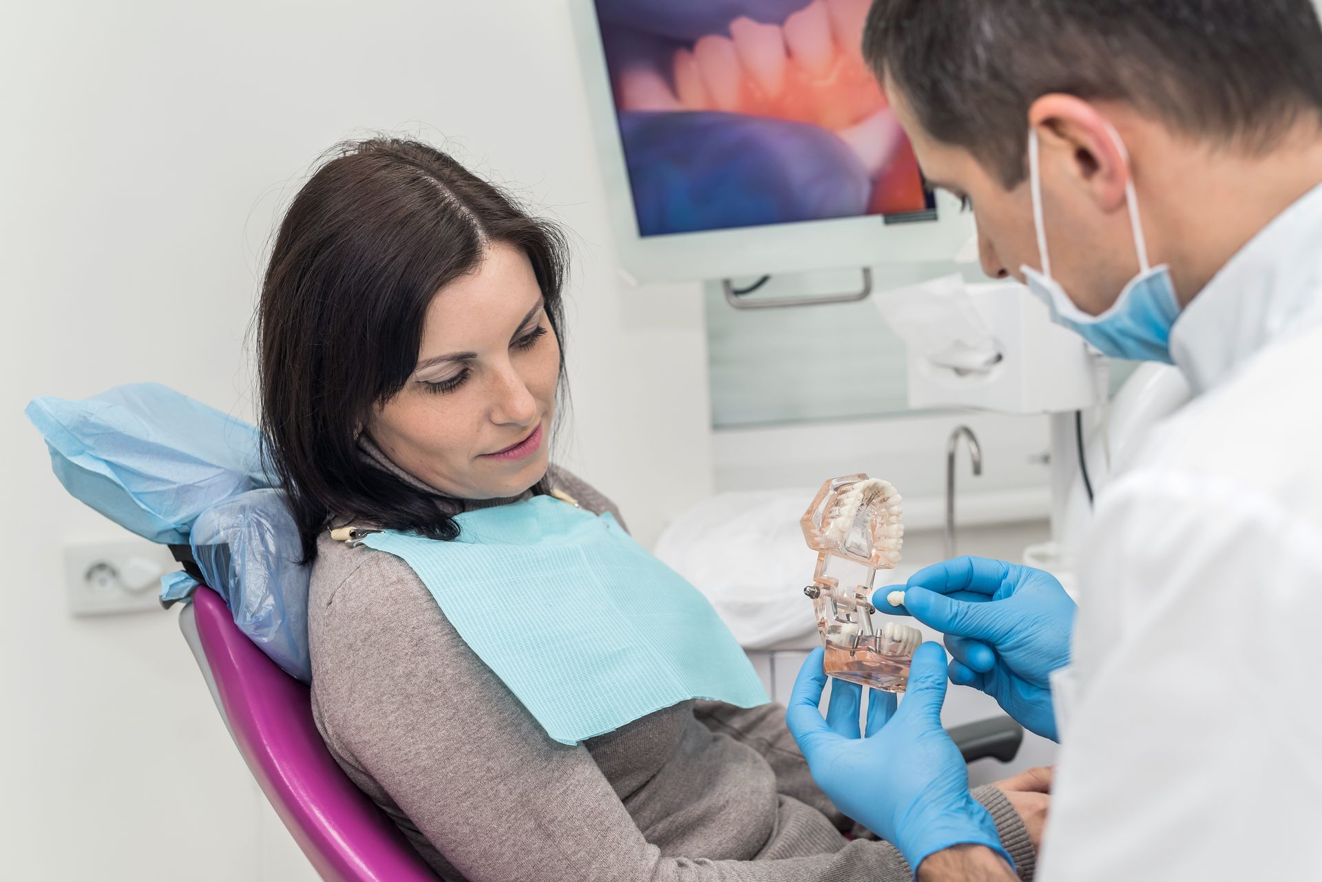 A dentist is explaining how dental crowns work to a patient.