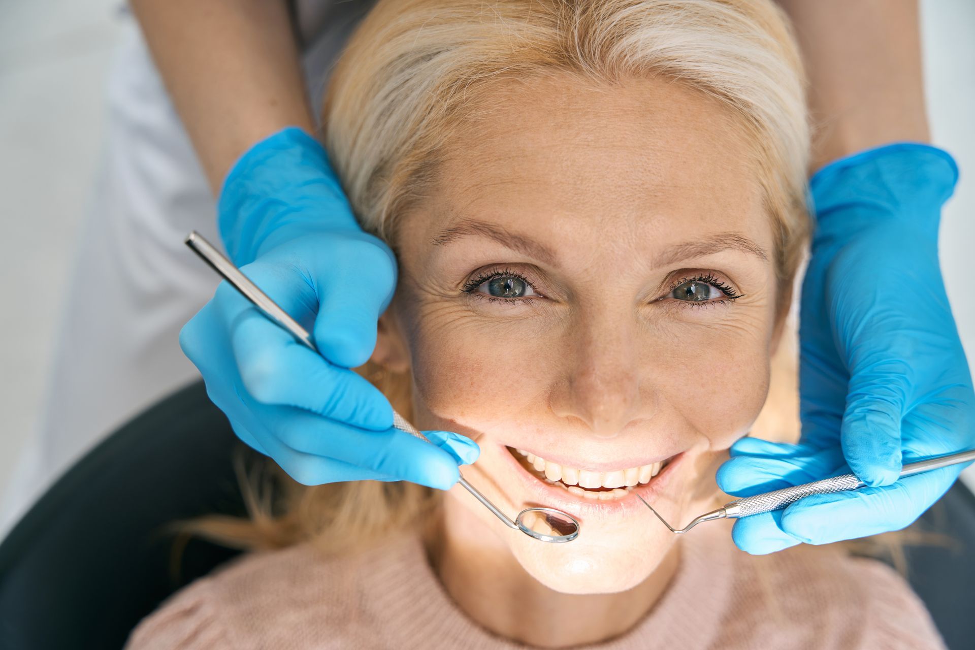Woman getting teeth cleaned by dentist, essential for dental crowns and oral health.