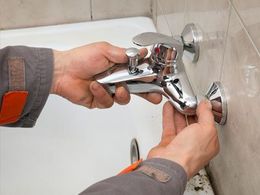 Plumber hands fixing water tap in a bathroom