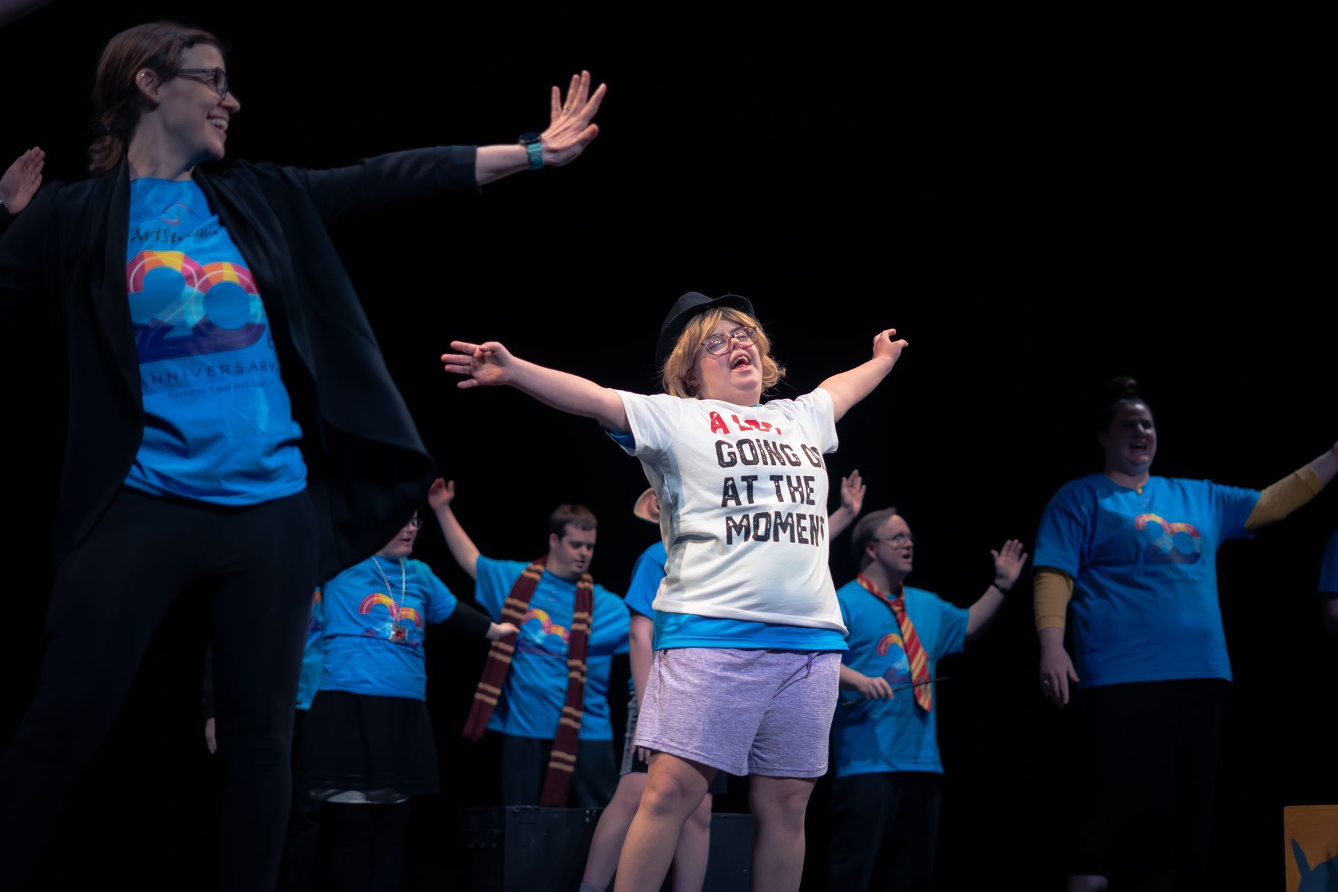 A group of people are performing on a stage with their arms outstretched.