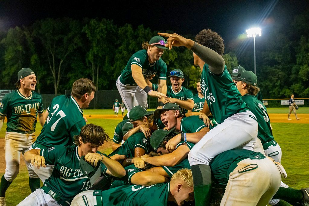 A group of Big Train baseball players are laying on top of each other on a field.