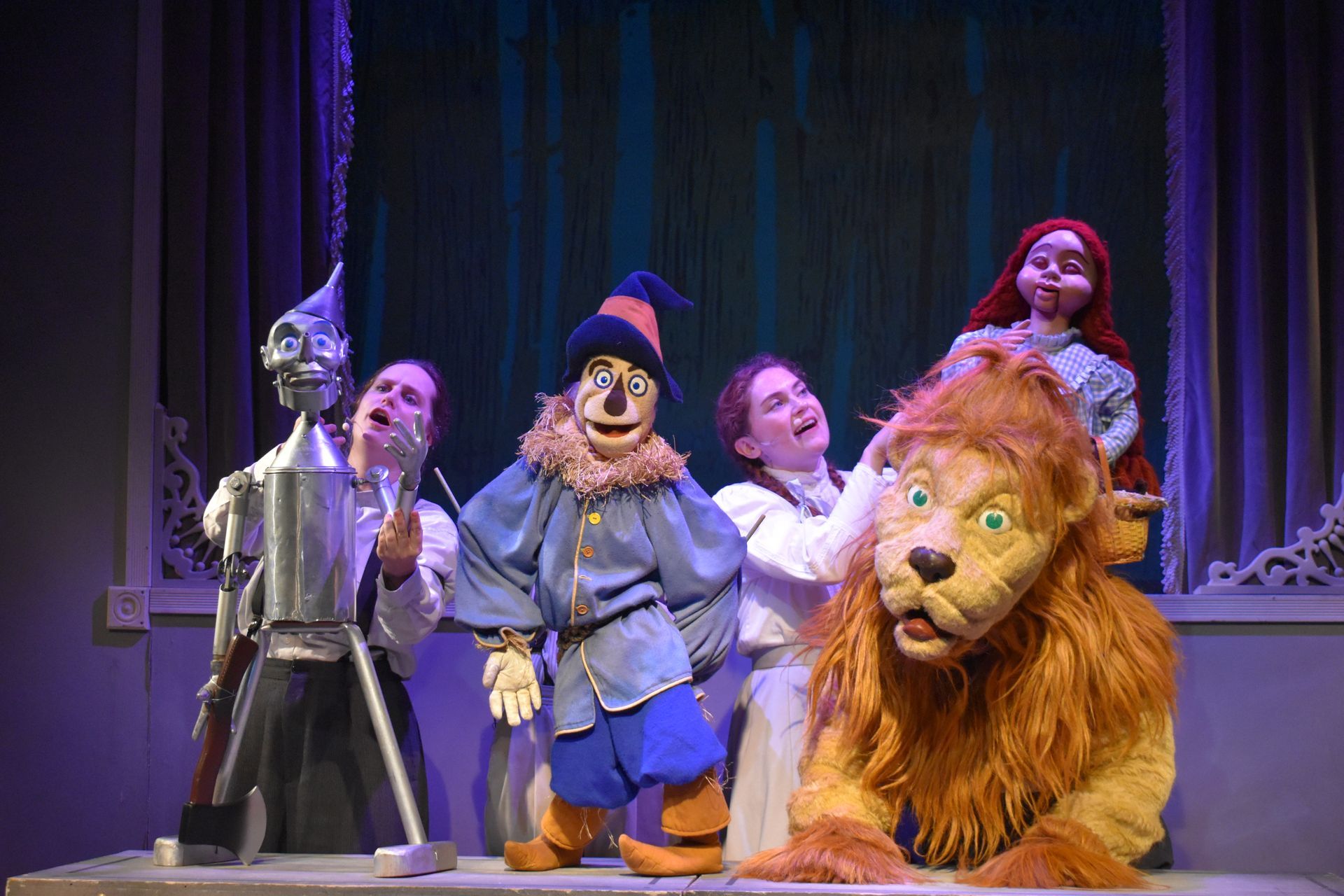 A group of puppets and puppeteers are standing next to each other on a stage.