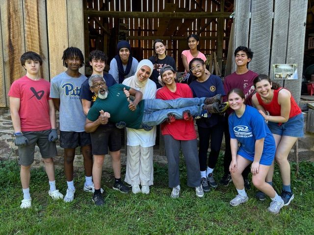 A group of people are posing for a picture in front of a barn.