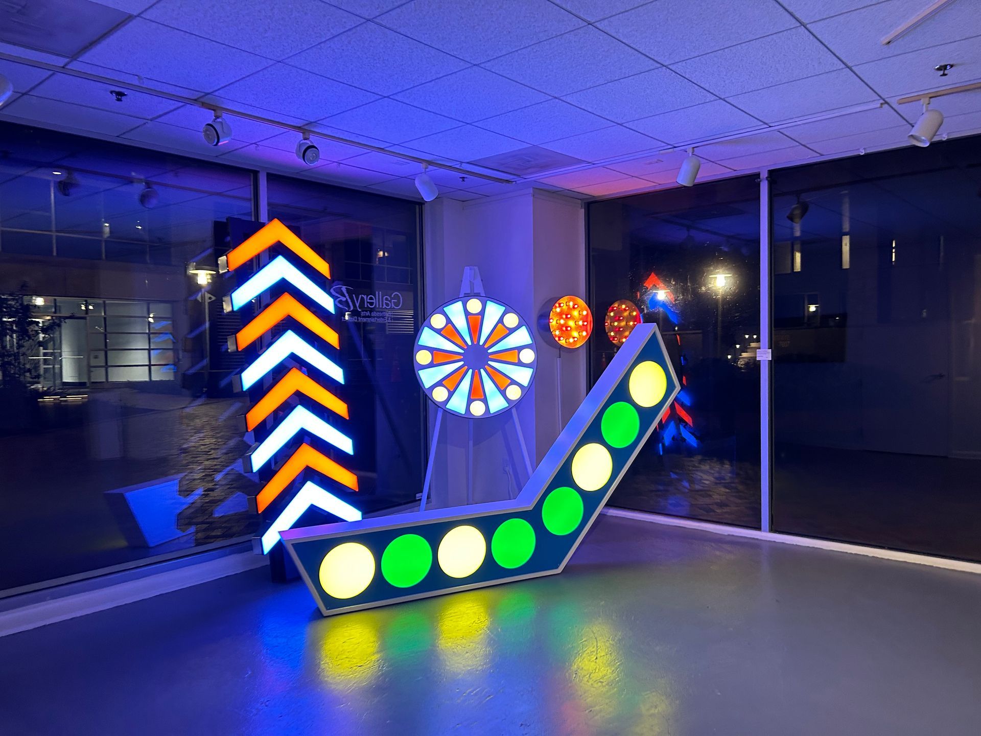 A large neon art display is sitting in a room next to a window.