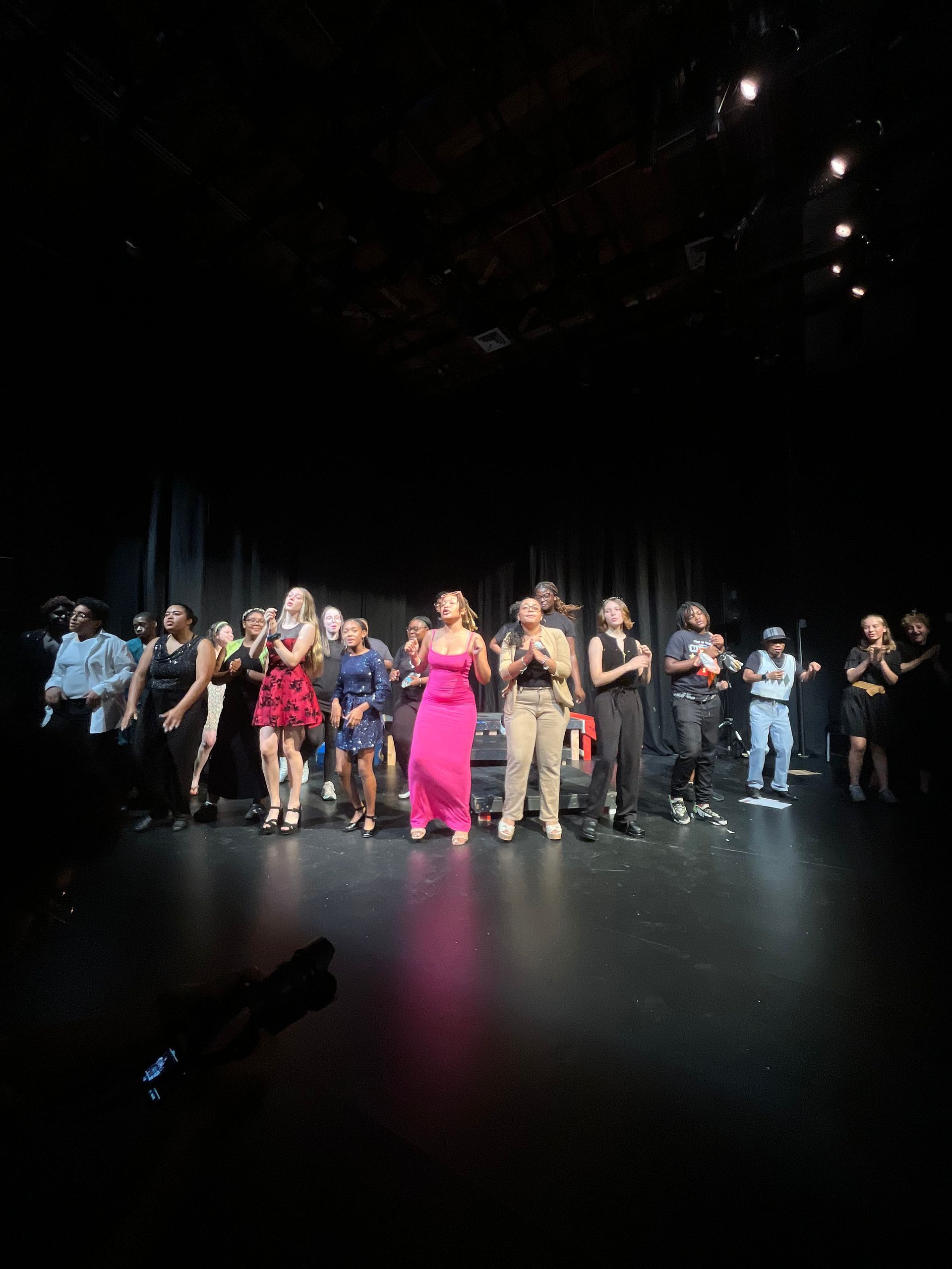 A group of people are performing on a stage in a dark room.
