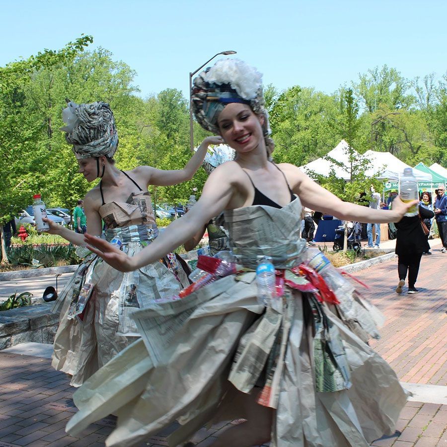 Two women wearing dresses made out of newspaper and plastic bottles