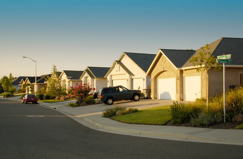 A black suv is parked in front of a row of houses.