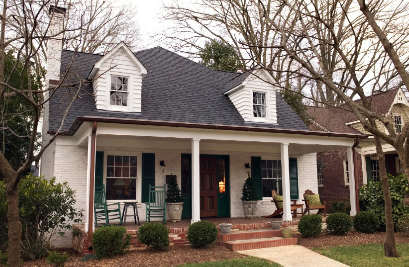 A white house with a black roof and green shutters
