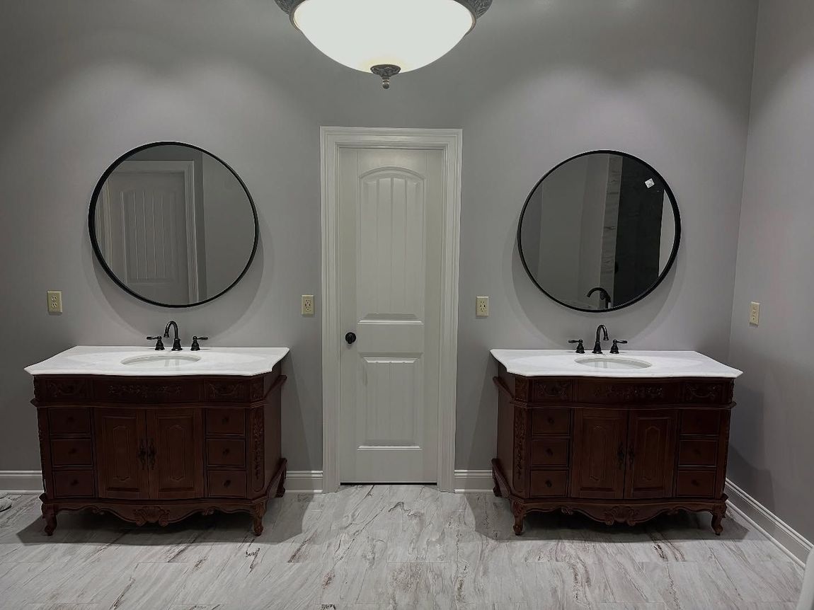 Two vanity sinks with round mirrors in a bathroom, door in the center.