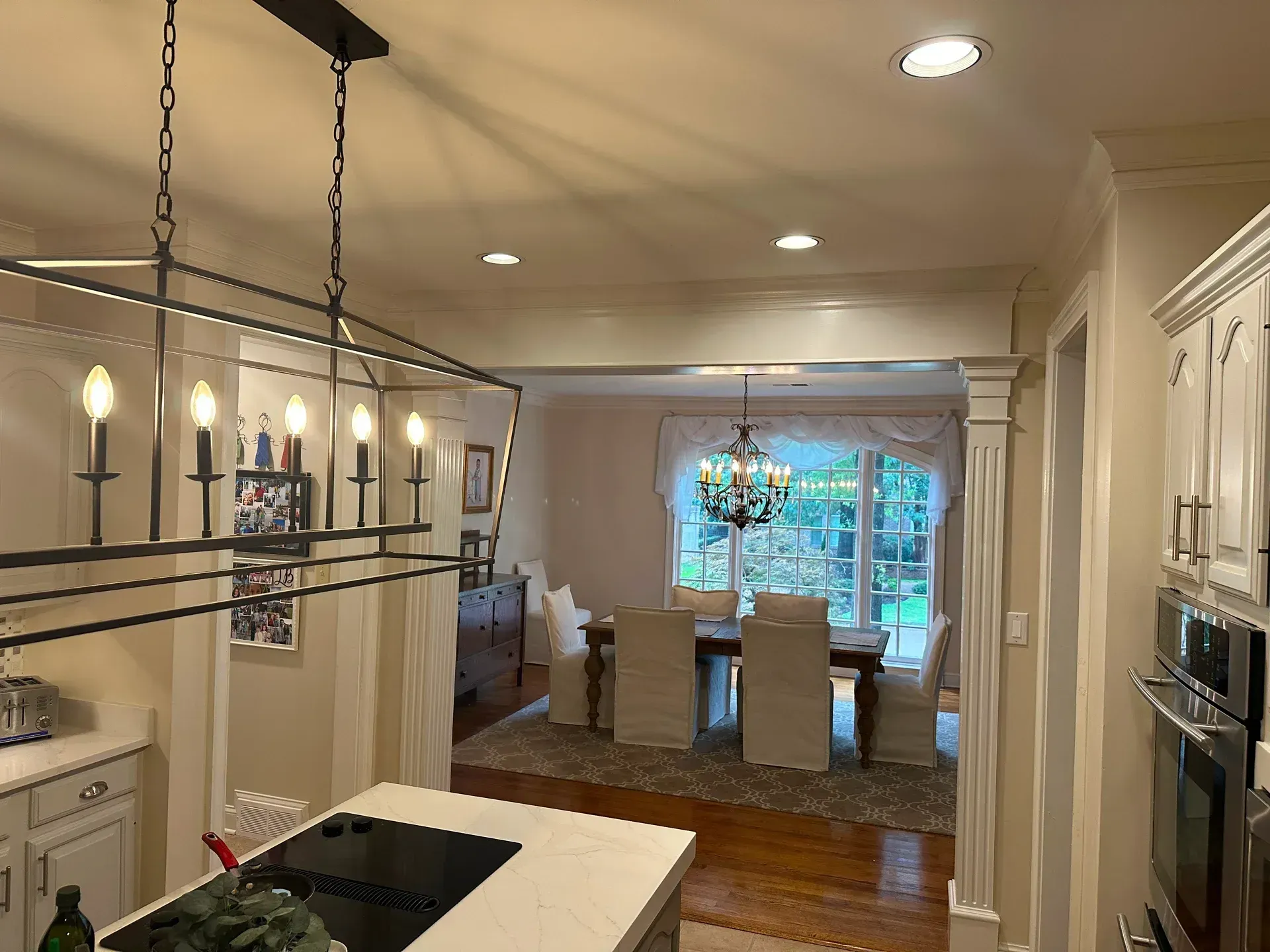 Kitchen and dining room open to each other; chandelier over table; black light fixture over island.