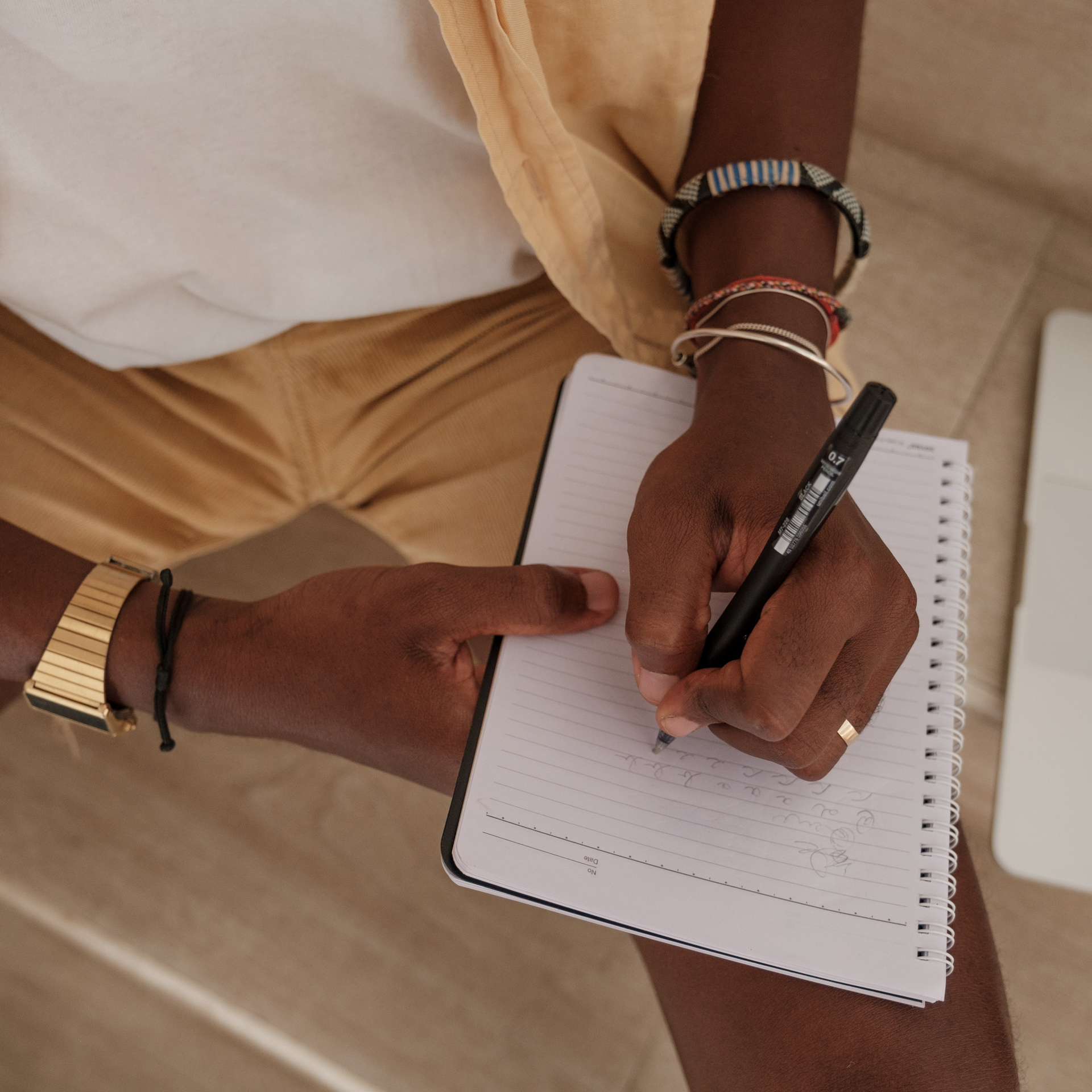 A person is writing in a notebook with a black pen