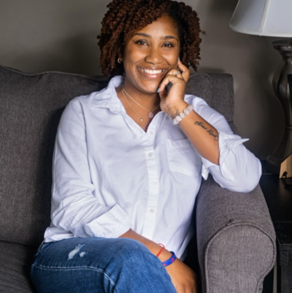 A woman is sitting in a chair talking on a cell phone