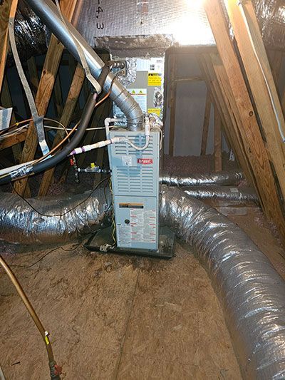 HVAC unit in an attic setting, with ductwork extending from the unit.