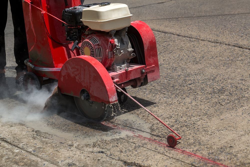 Red Concrete Saw Cutting a Line in Asphalt — Cairns Electrical Rewinds & Repairs In Bungalow, QLD