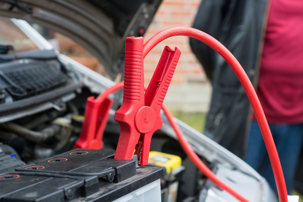 Red Jumper Cables Attached to a Car Battery — Cairns Electrical Rewinds & Repairs In Bungalow, QLD