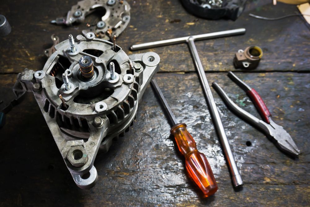 Disassembled Car Alternator With Tools on a Wooden Surface — Cairns Electrical Rewinds & Repairs In Innisfail, QLD