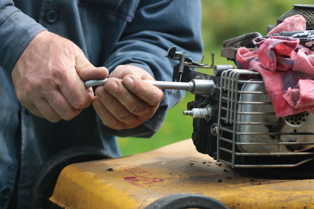 Hands Holding a Wrench, Working on a Small Engine — Cairns Electrical Rewinds & Repairs In Port Douglas, QLD