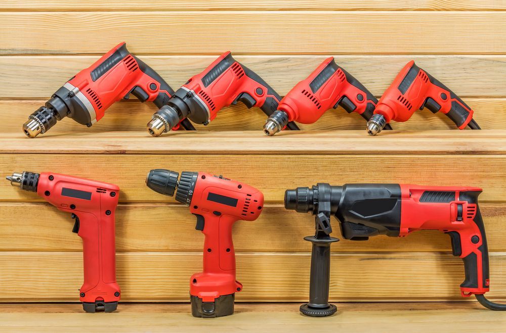 Red Power Drills Lined Up on Wooden Surface — Cairns Electrical Rewinds & Repairs In Bungalow, QLD