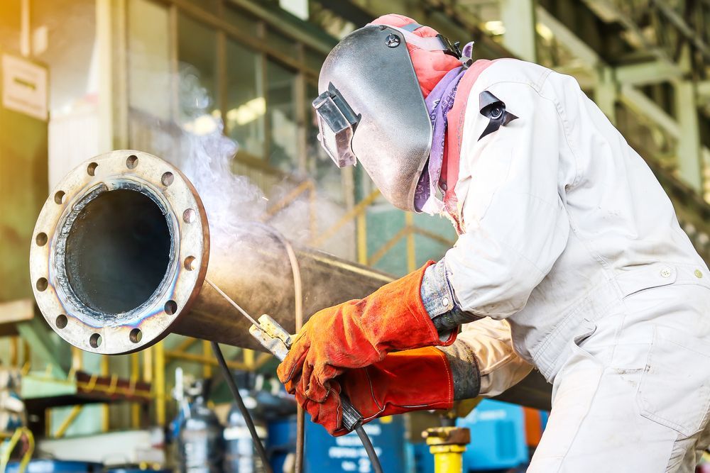 Welder in Protective Gear Welding a Large Metal Pipe — Cairns Electrical Rewinds & Repairs In Townsville, QLD