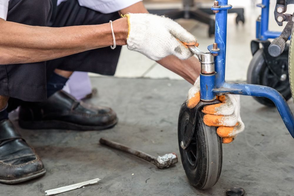 Person in Gloves Repairs a Blue Wheelchair's Wheel — Cairns Electrical Rewinds & Repairs In Townsville, QLD