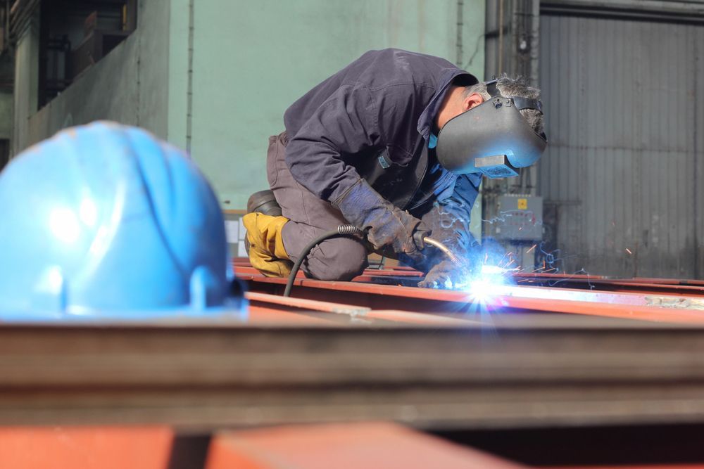 Welder Wearing Protective Gear Welds a Metal — Cairns Electrical Rewinds & Repairs In Bungalow, QLD