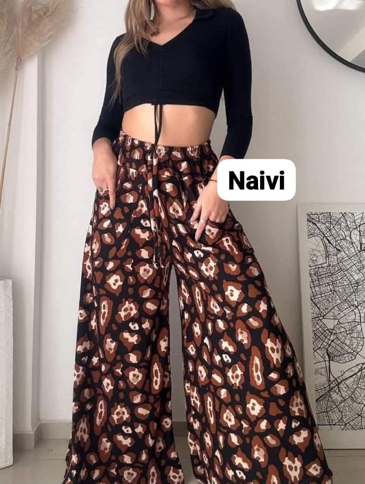 Una mujer que lleva un top corto negro y pantalones anchos con estampado de leopardo.