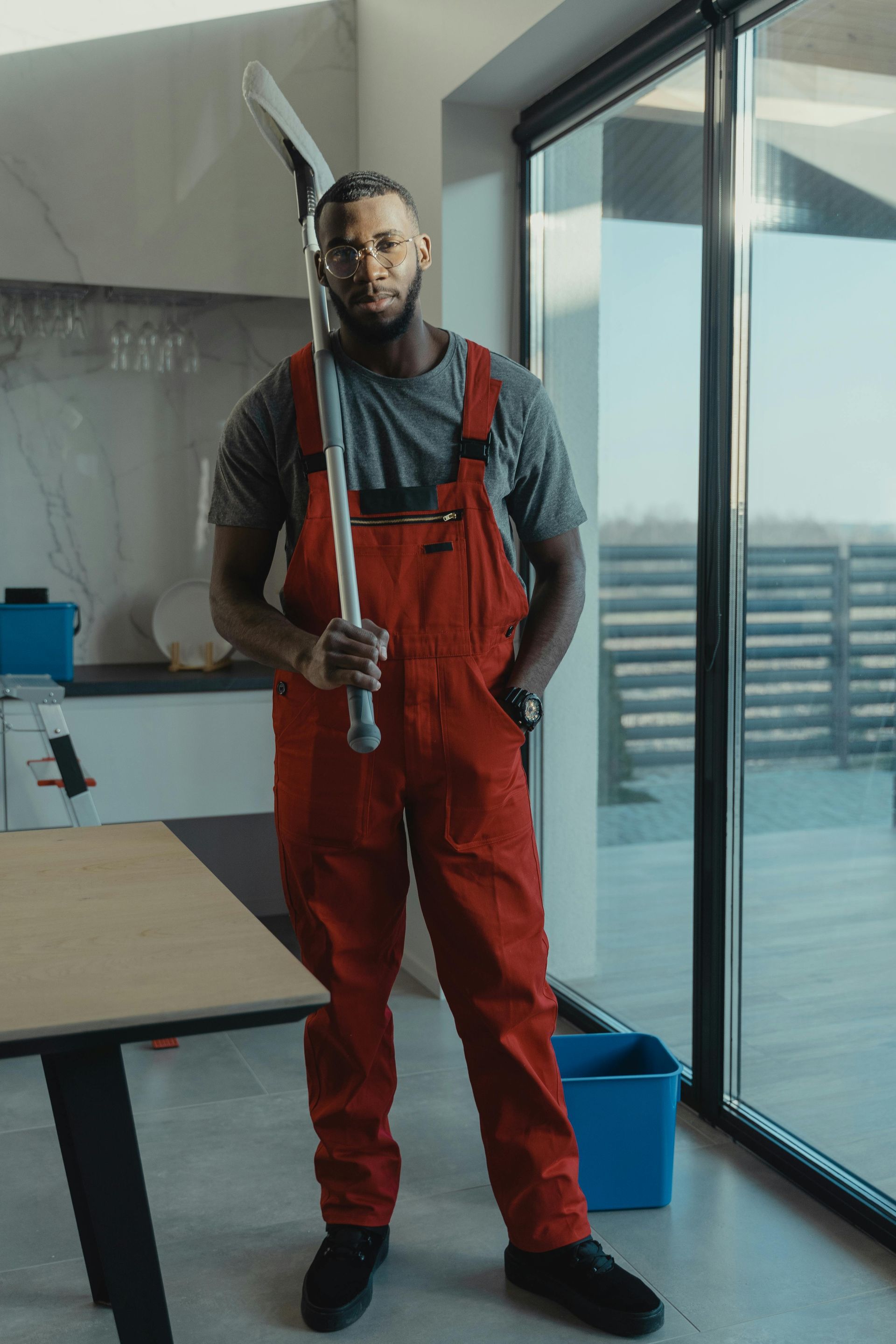 Professional janitor in red coveralls holding cleaning supplies in modern office