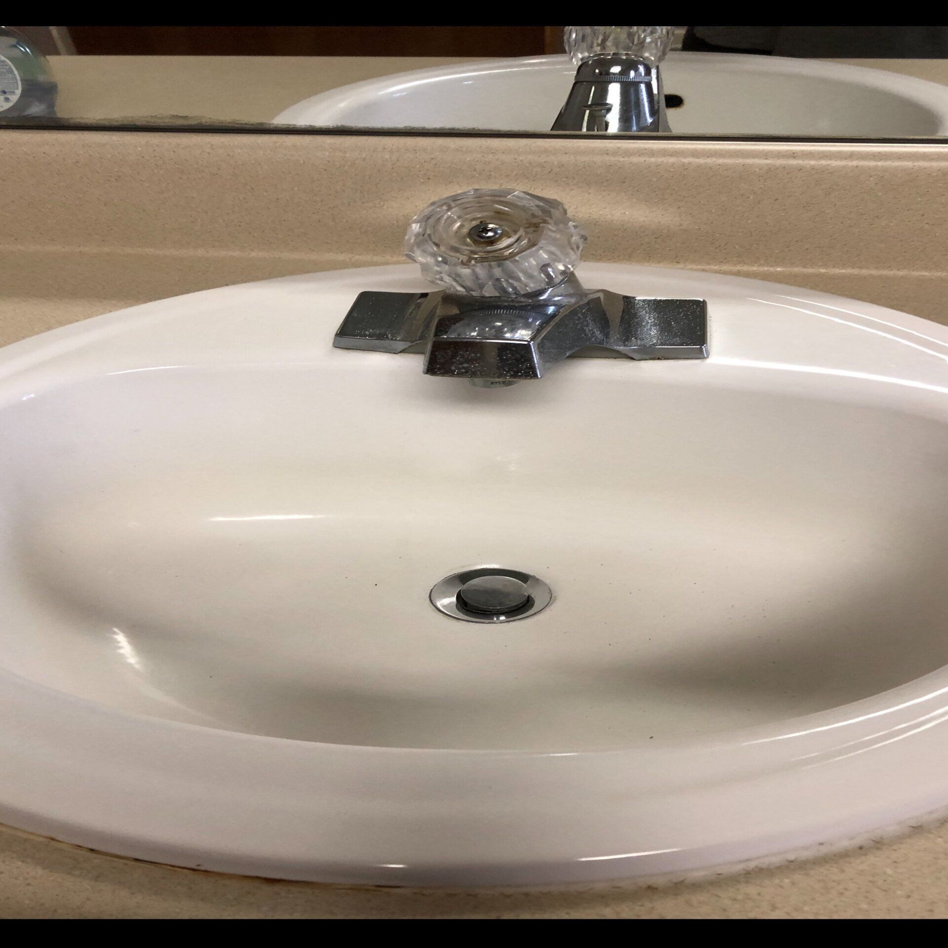 White bathroom sink with chrome faucet and drain.