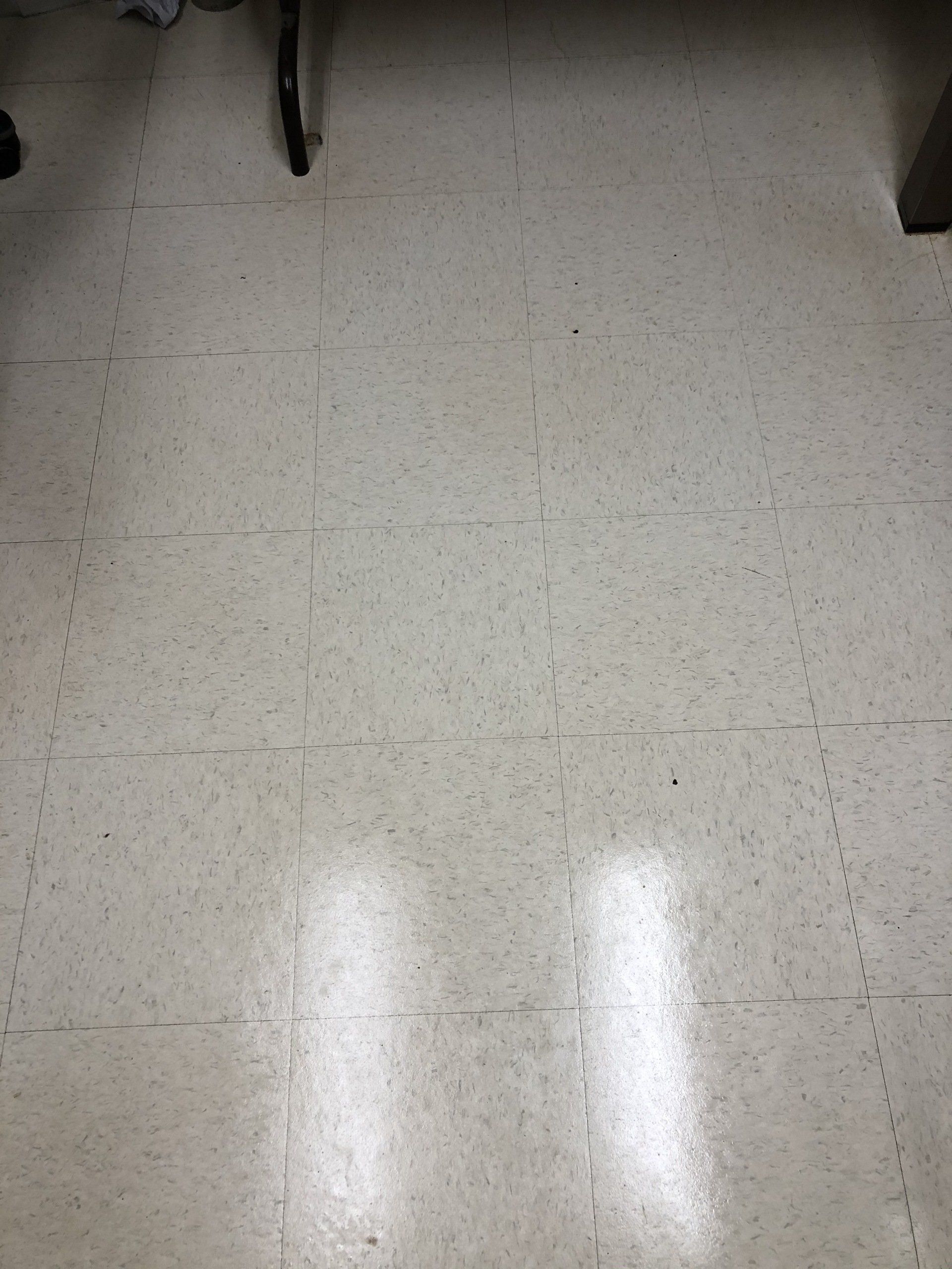 Off-white speckled linoleum floor tiles with dark grout lines.