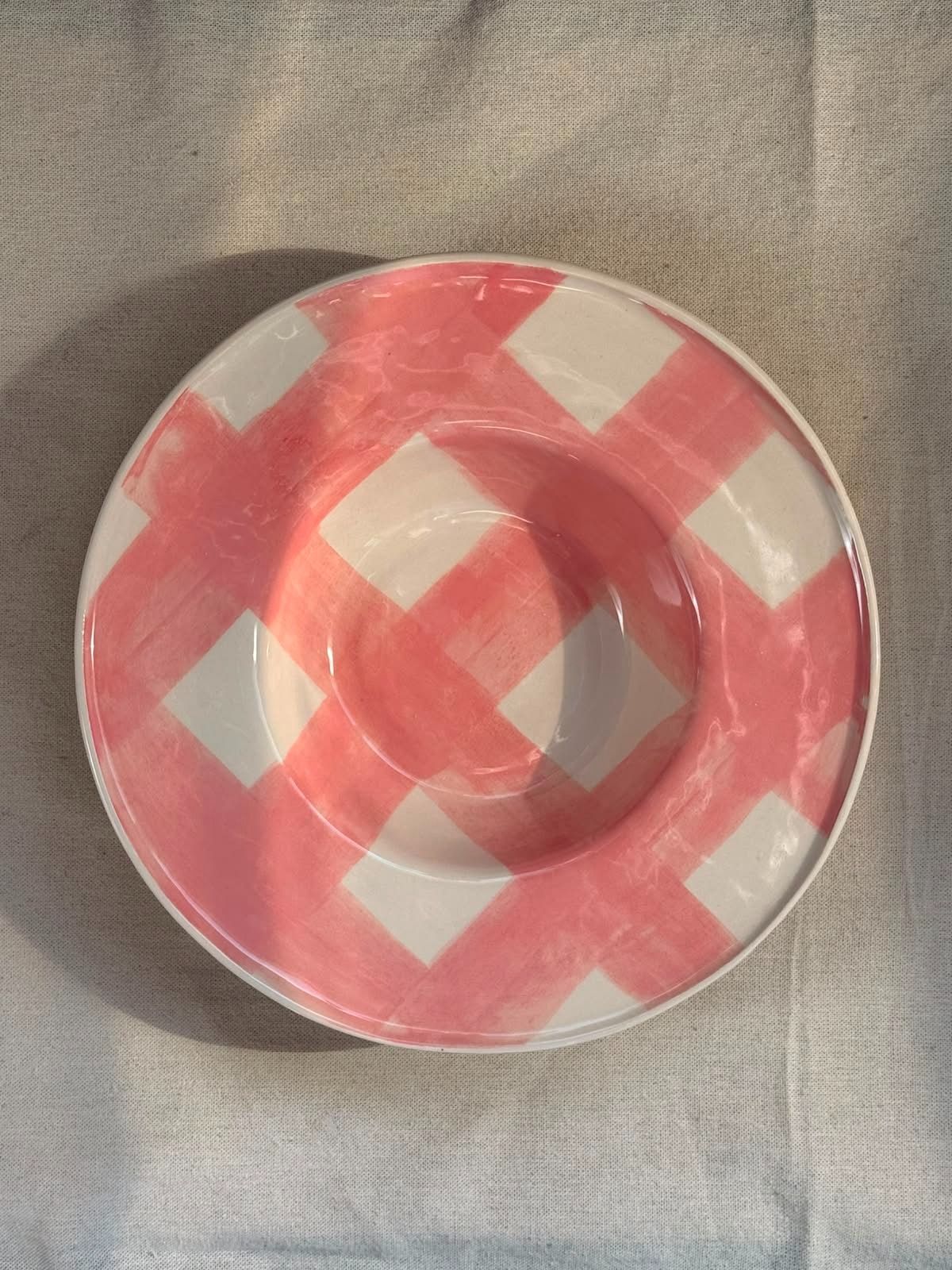 Plato redondo estampado en rosa y blanco sobre un fondo de tela gris.