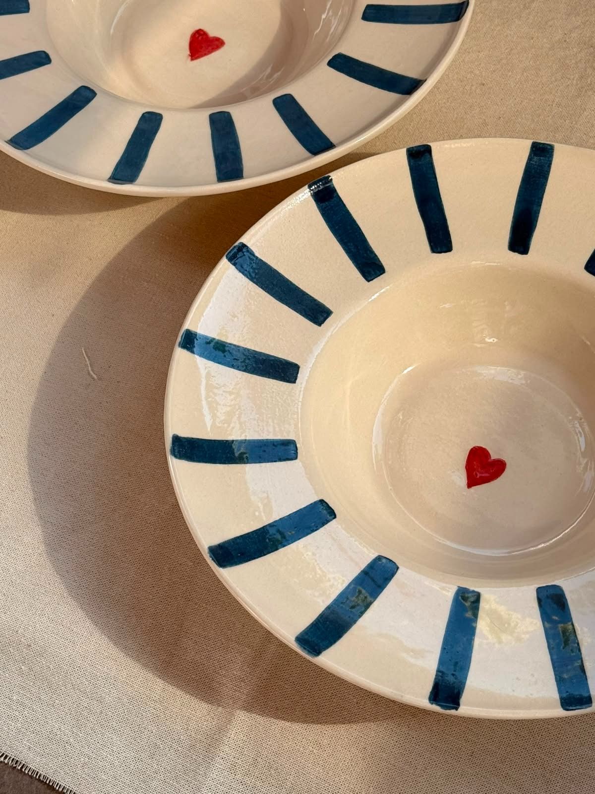 Plato de papel blanco con rayas radiales azules y un pequeño corazón rojo en el centro.