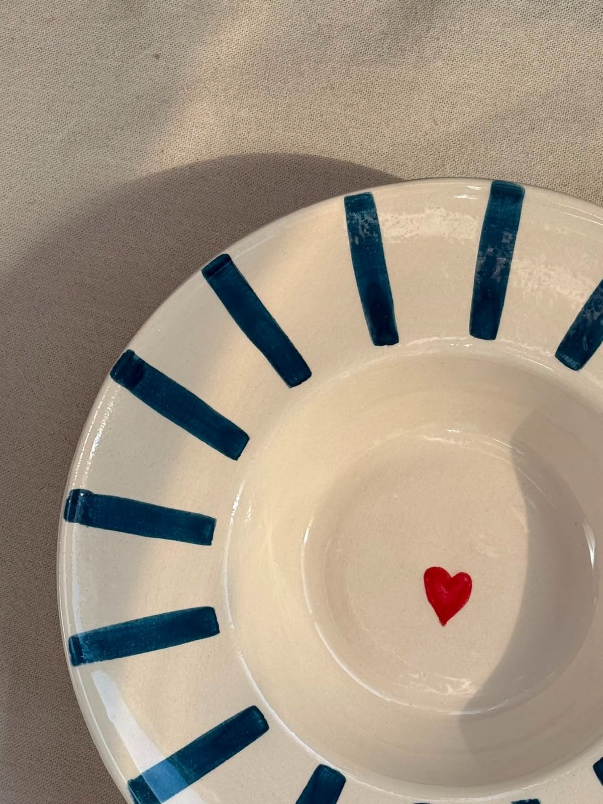 Plato de papel blanco con rayas radiales azules y un pequeño corazón rojo en el centro.