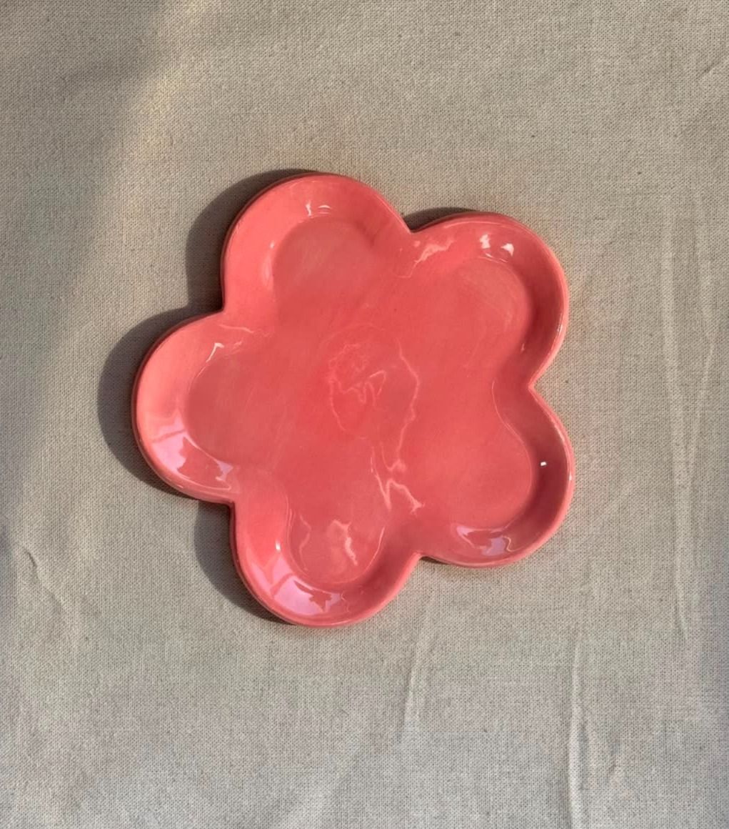 Platos de cerámica rosa con forma de flor sobre un fondo de tela clara.
