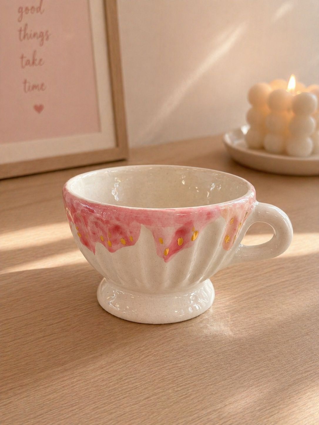 Taza de té de cerámica rosa y blanca sobre una mesa de madera bajo una suave luz del sol.