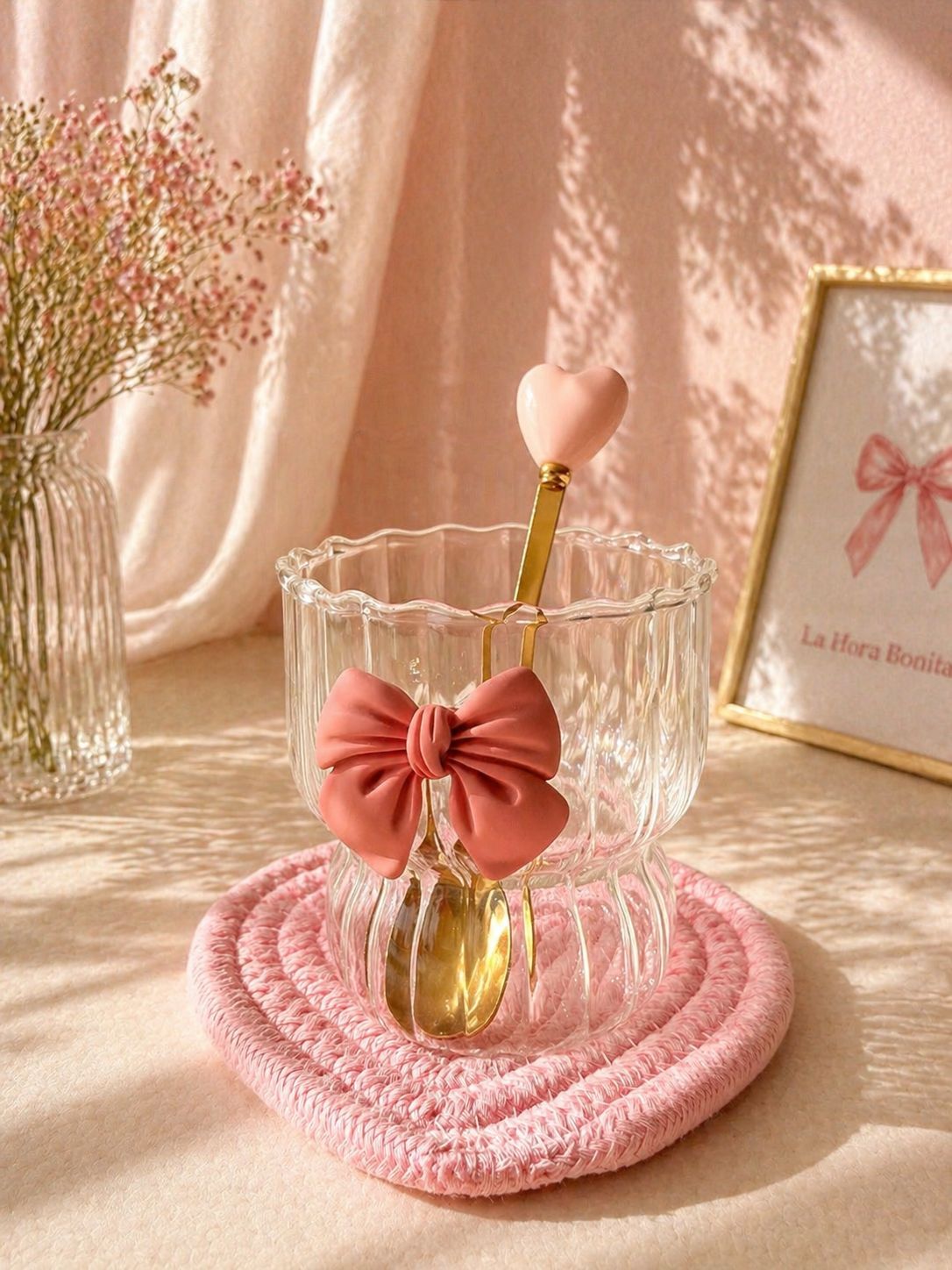 Vaso decorativo rosa con pajita en forma de corazón sobre un posavasos texturizado en un entorno de tonos pastel suaves.