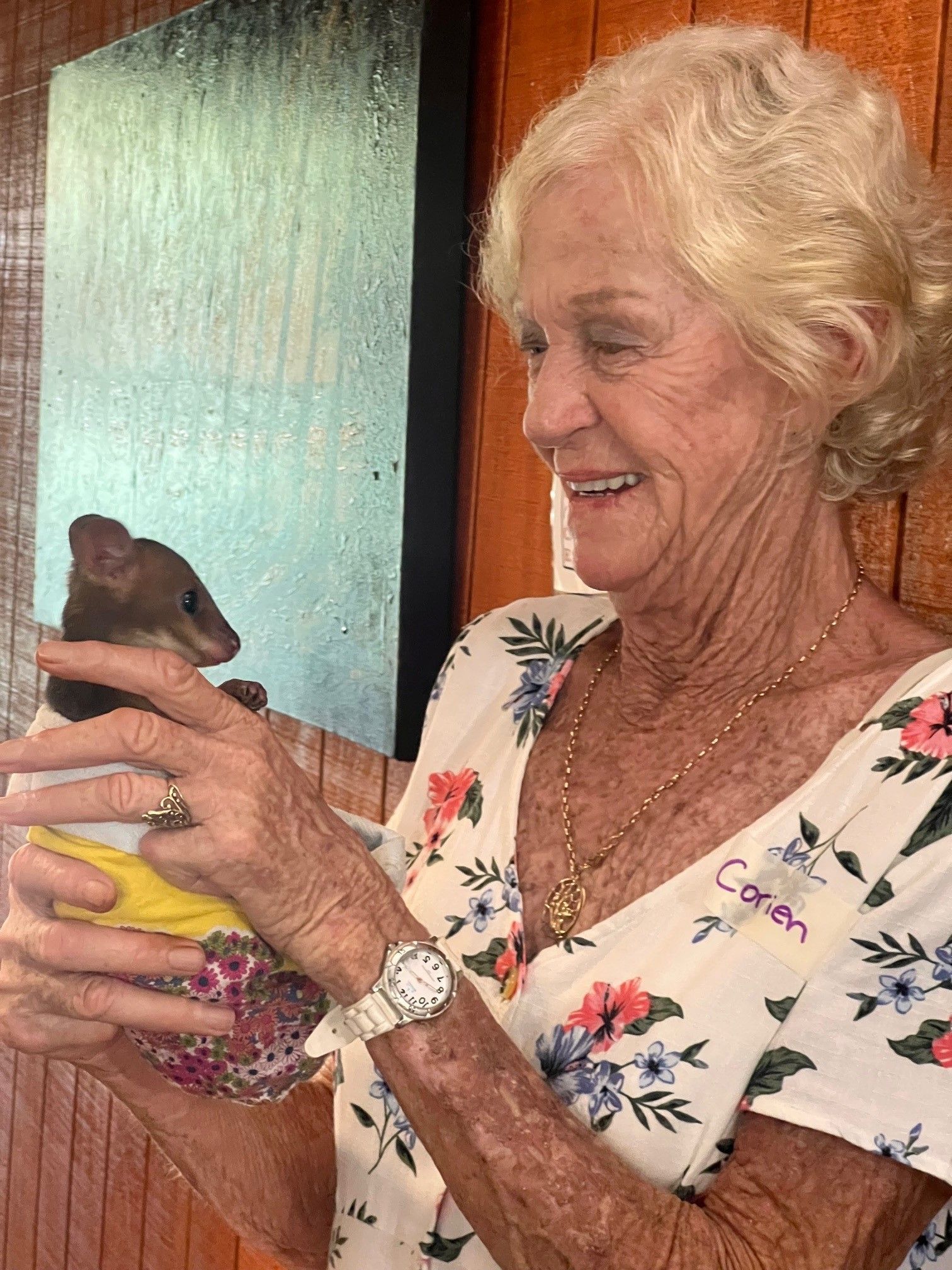 An elderly woman is holding a small animal in her hands.