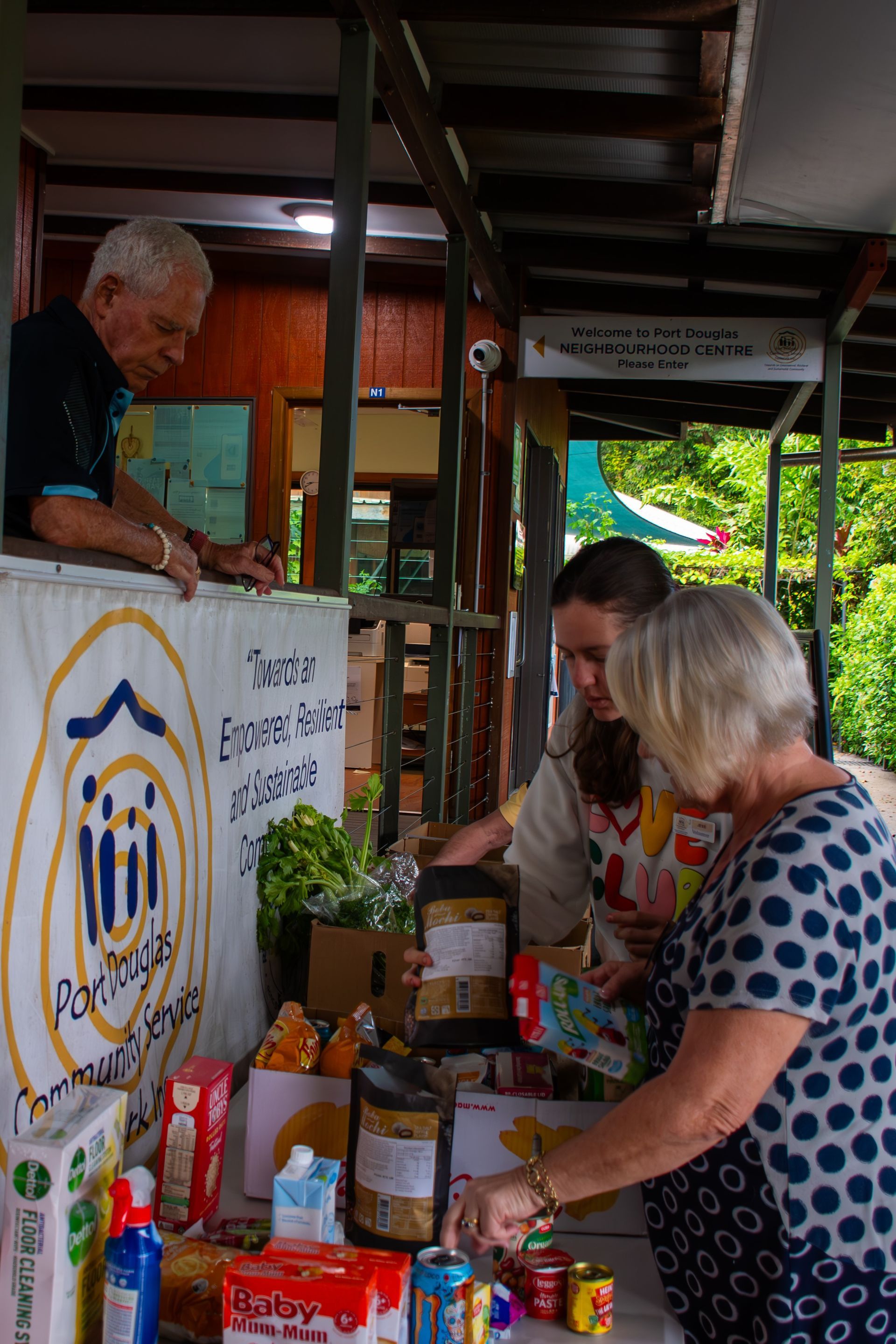 A group of people are standing around a table filled with food.