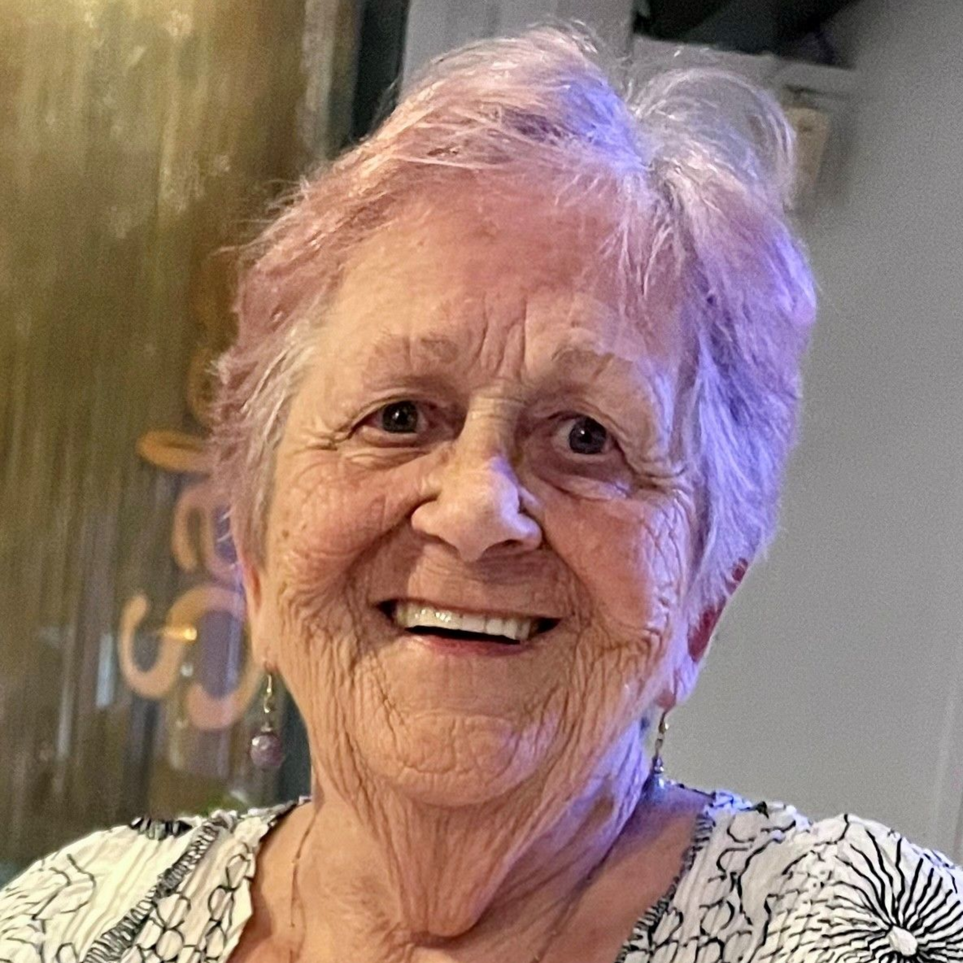 A woman in a grey jacket is smiling with her arms crossed