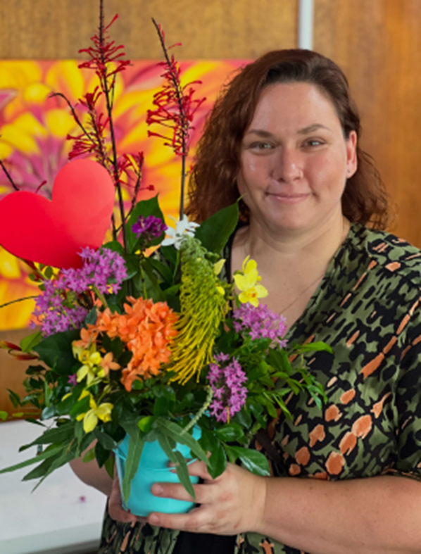 A woman is holding a bouquet of flowers in a blue pot