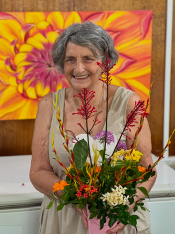 A woman is holding a bouquet of flowers in front of a painting of flowers