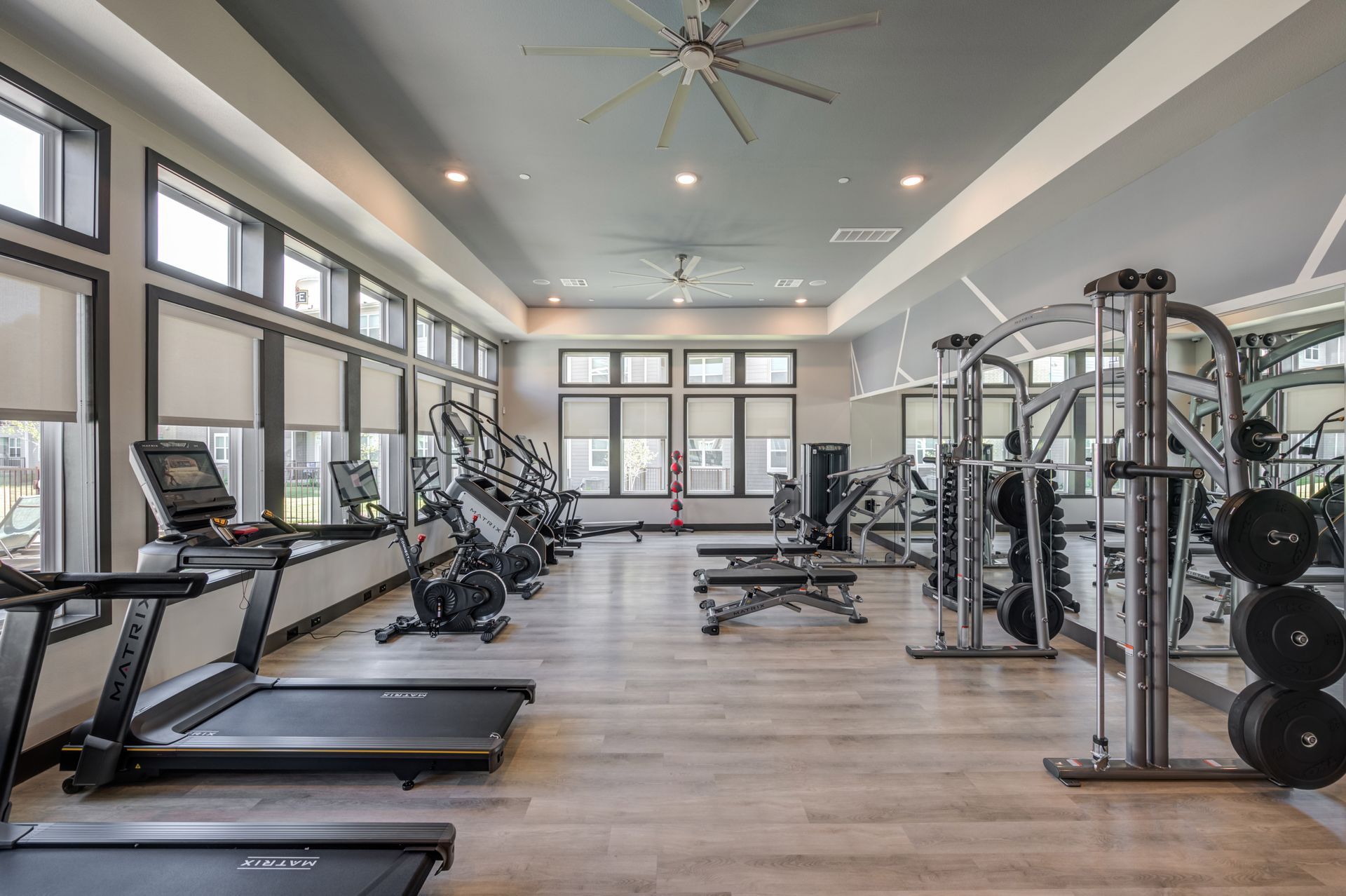 A large gym with treadmills , exercise bikes , and a ceiling fan at The Jameson.