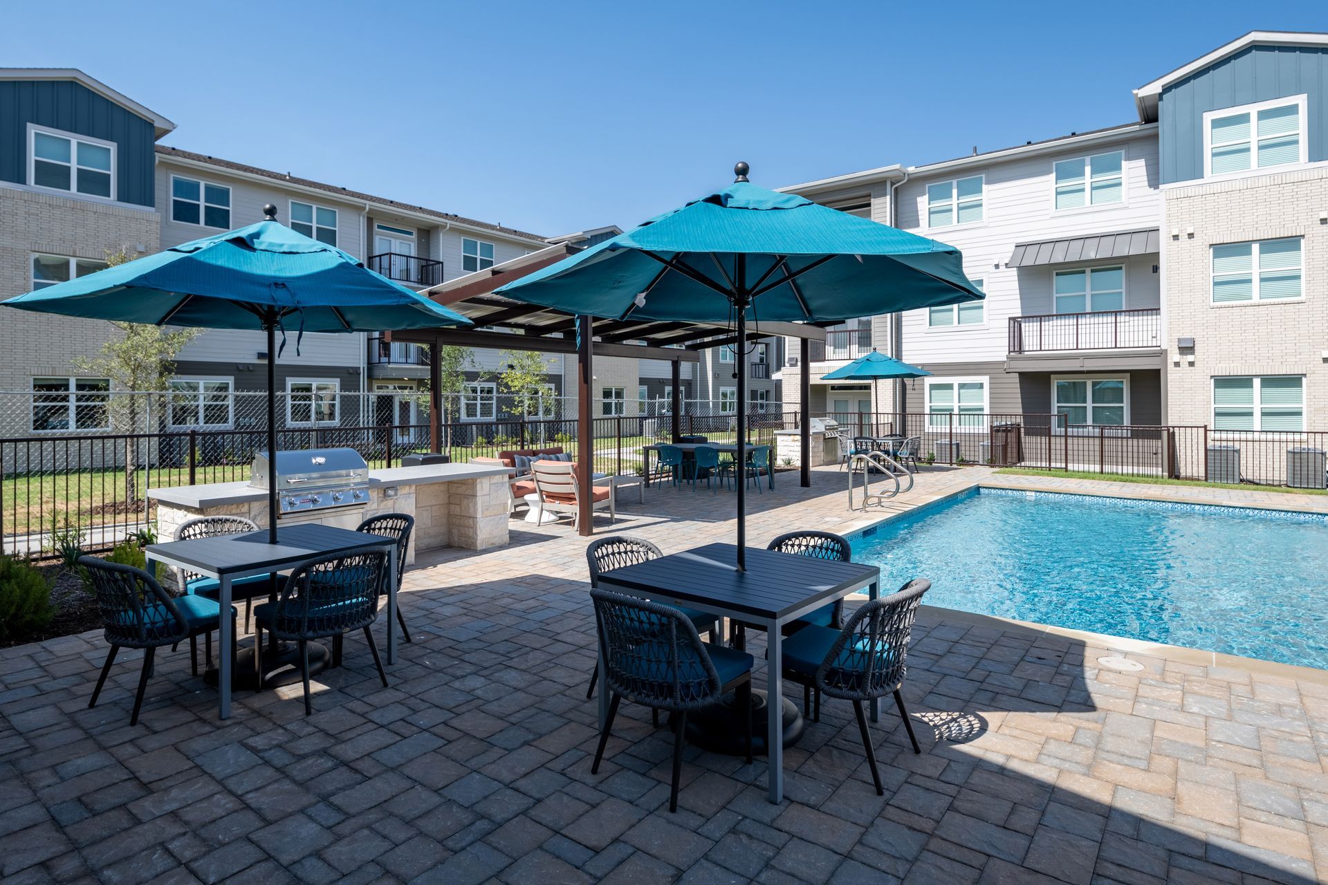 A swimming pool with tables and chairs and umbrellas in front of a building at The Jameson.