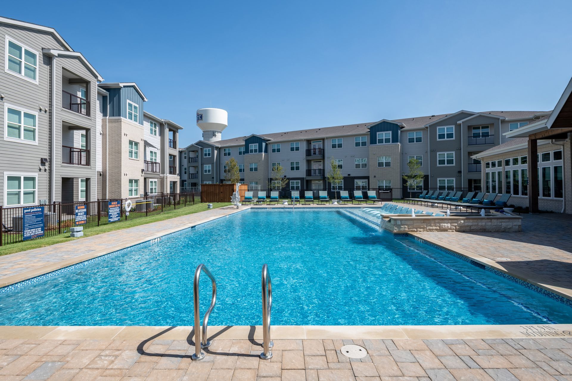 A large swimming pool in front of a large apartment building at The Jameson.
