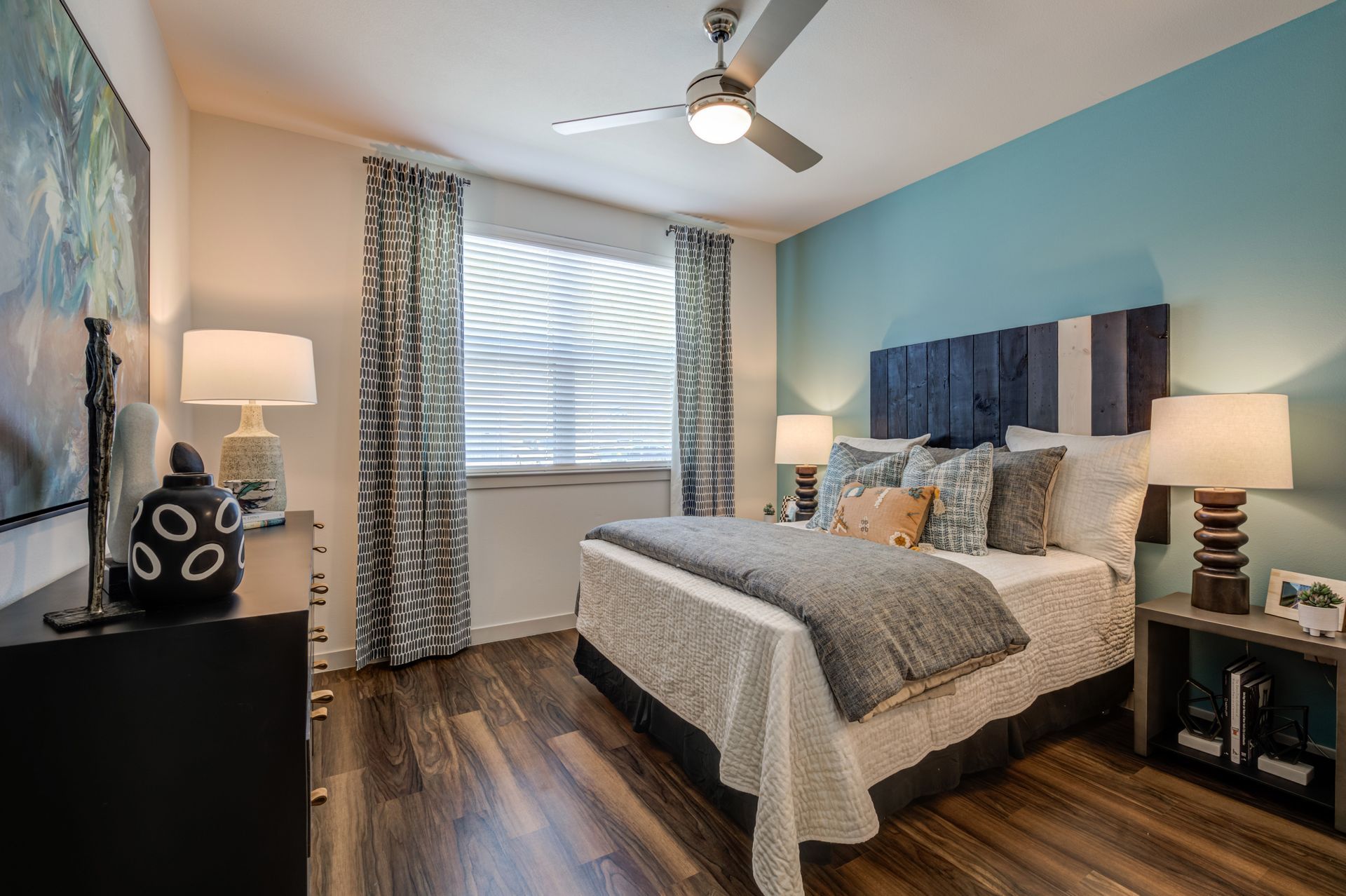 A bedroom with a bed , dresser , lamps and a ceiling fan at The Jameson.