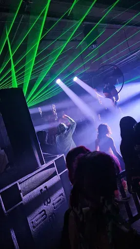 Green laser lights over a dancing crowd in a dim club.
