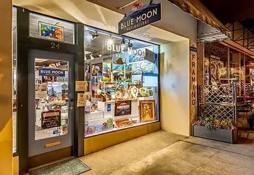 Blue Moon storefront at night with lit display windows and a sidewalk entrance