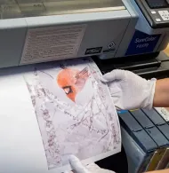 Gloved hand holds up a cracked print from a large-format printer