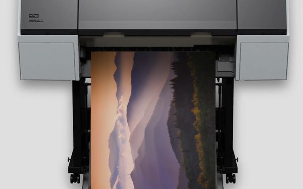 Large-format printer outputting a landscape photo with mountains and sunset colors